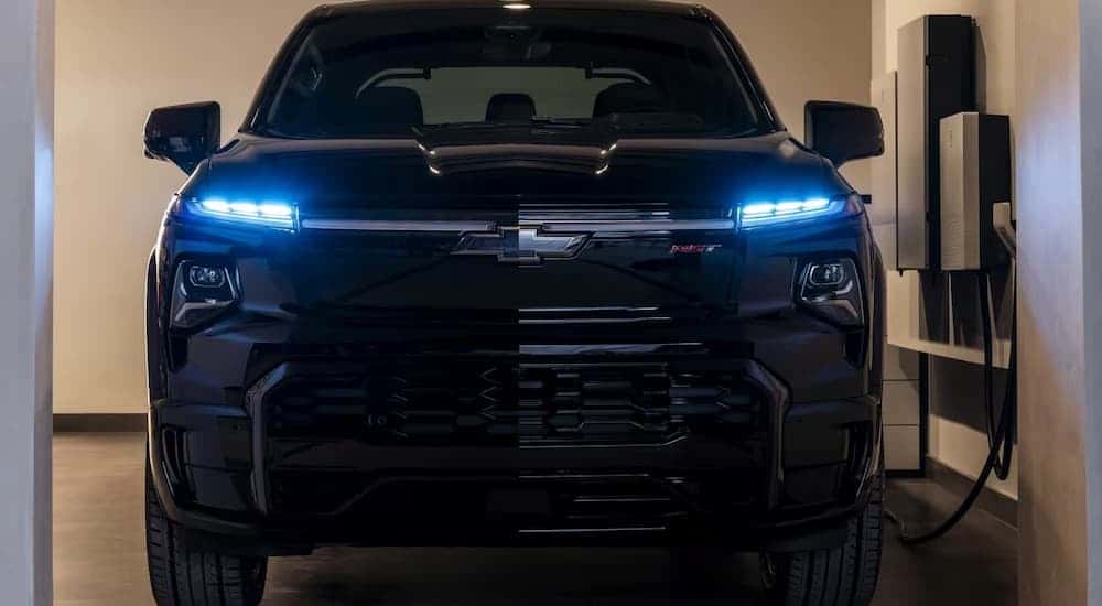 A black 2025 Chevy Silverado EV charging in a garage