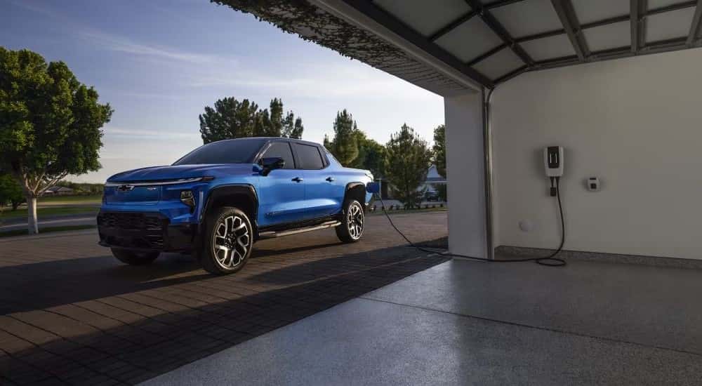A blue 2025 Chevy Silverado EV parked in a driveway charging