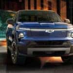 Head on view of a blue 2025 Chevy Silverado EV parked in front of a building.