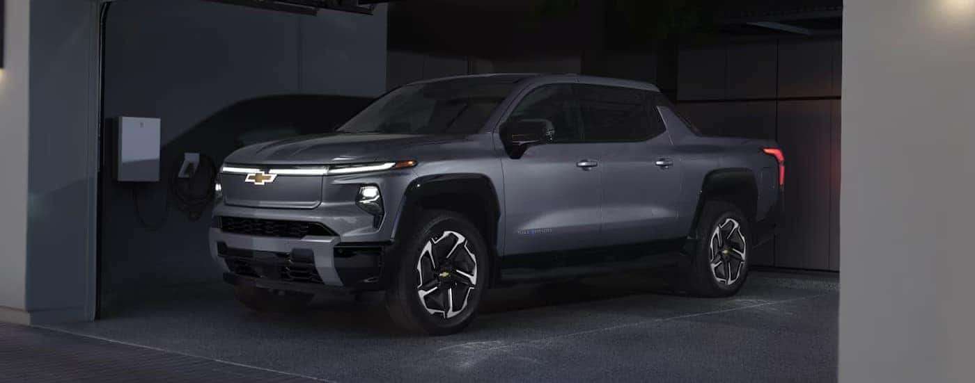 A silver 2025 Chevy Silverado EV charging in a garage.