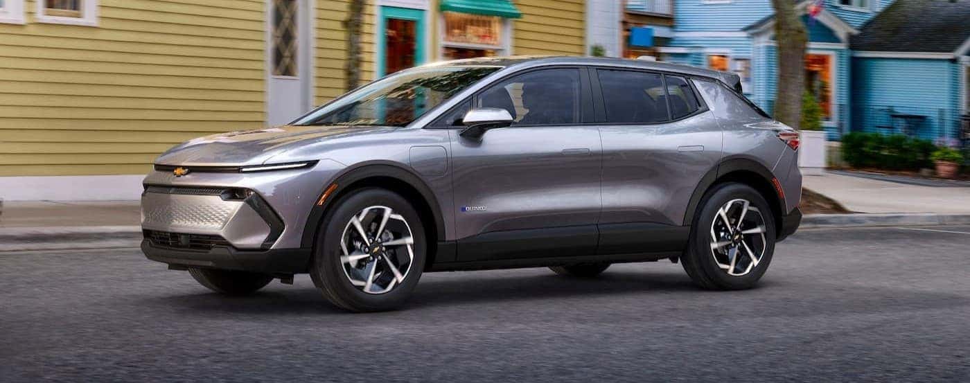 A silver 2024 Chevy Equinox EV driving in a city.