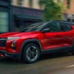 Red 2025 Chevy Equinox vs 2025 Hyundai Tucson from the front at an angle driving down a city street.