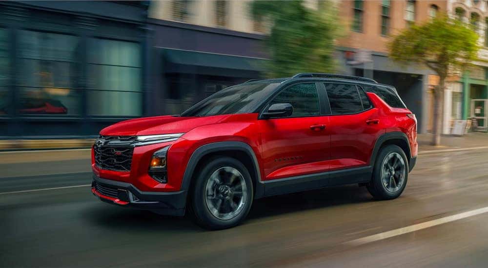 Red 2025 Chevy Equinox vs 2025 Hyundai Tucson from the front at an angle driving down a city street.