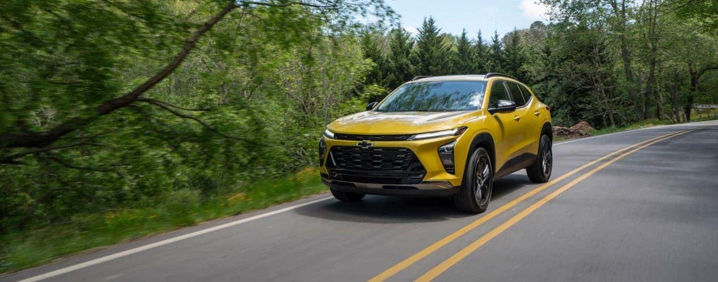 A yellow 2024 Chevy Trax driving on a highway after visiting a Chevy dealer near Niskayuna.