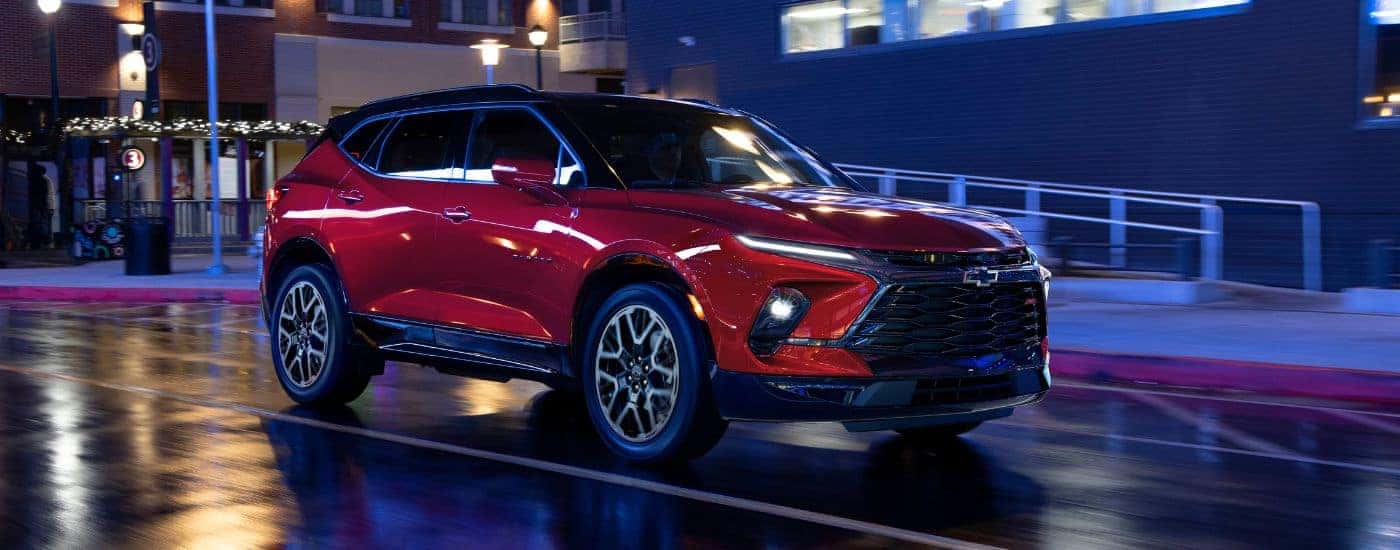 A red 2025 Chevy Blazer RS driving down a wet city street