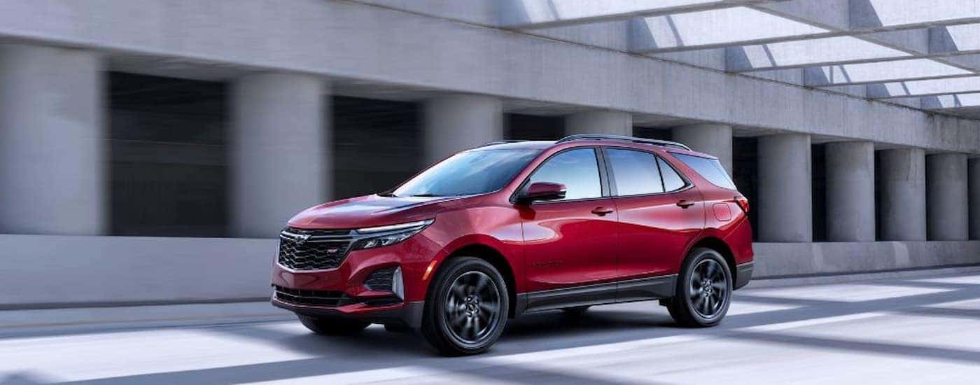 A red 2022 Chevy Equinox RS from a used car dealership driving down a street
