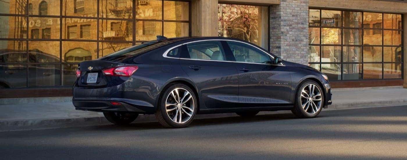 A black 2023 Chevy Malibu parked outside a building in a city