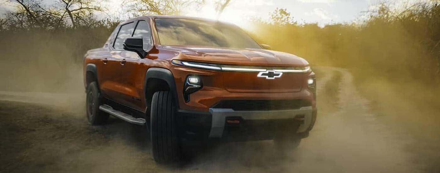 A red 2025 Chevy Silverado EV off-roading on a dirt road