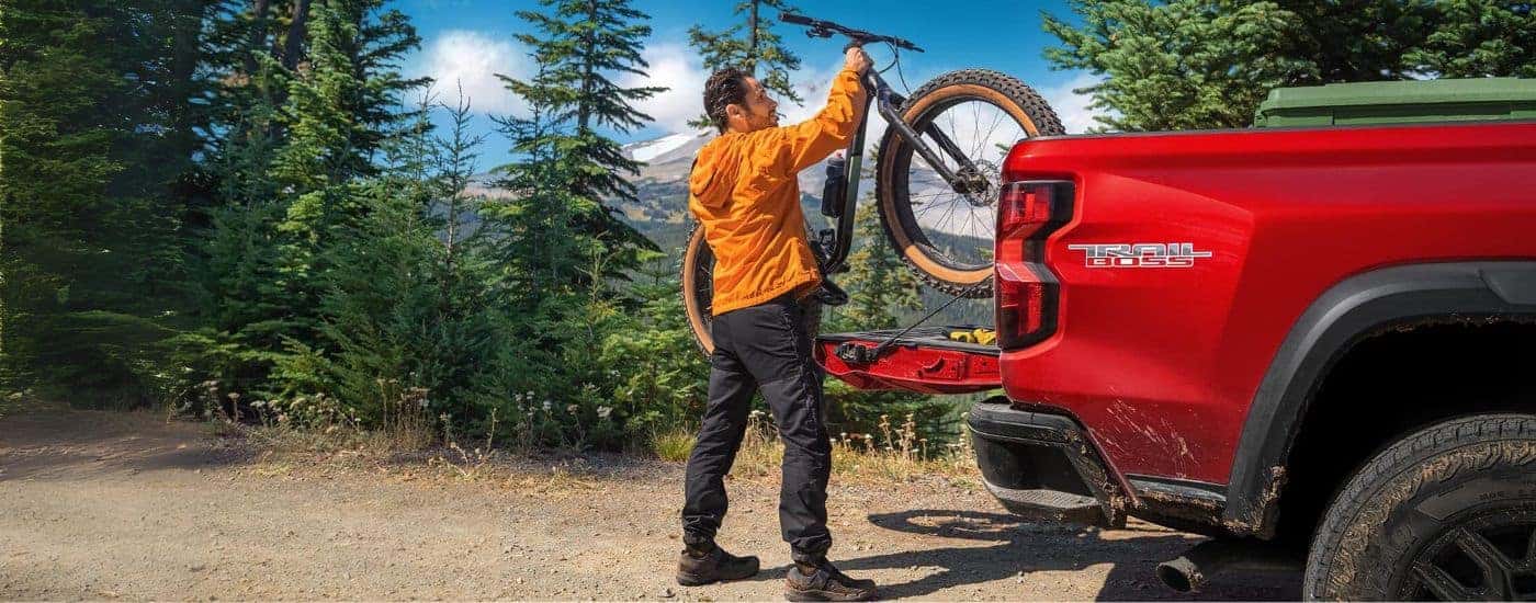 A person get the bike out of the bed of their red 2023 Chevy Colorado Trail Boss