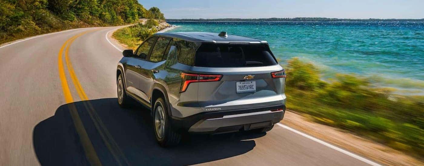 A silver 2026 Chevy Equinox driving near a lake.
