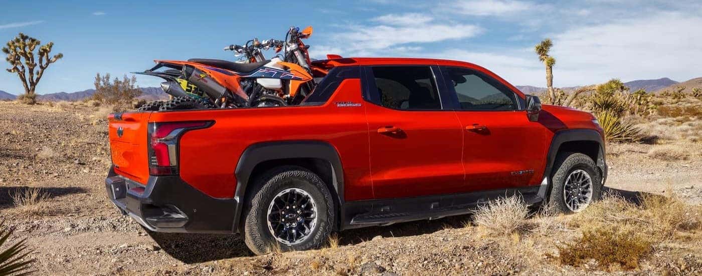 Dirt bikes in the bed of a red 2026 Chevy Silverado EV Trail Boss.