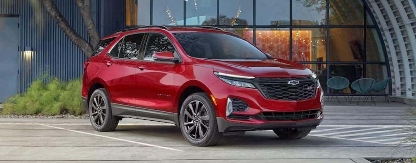 A red 2024 Chevy Equinox RS parked near a hangar.