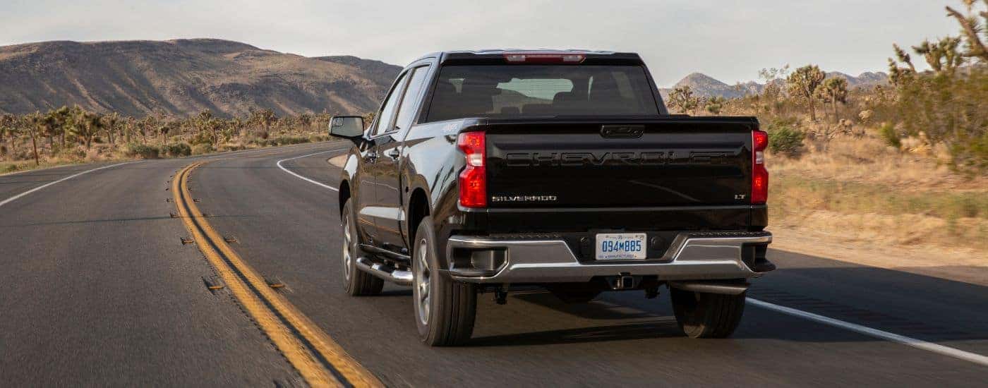 Black 2022 Chevy Silverado 1500 driving down the road from the rear
