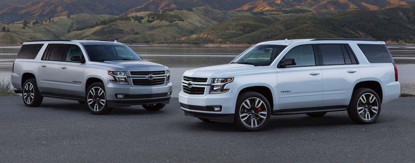 A white 2020 Chevy Tahoe parked next to a silver 2020 Chevy Suburban