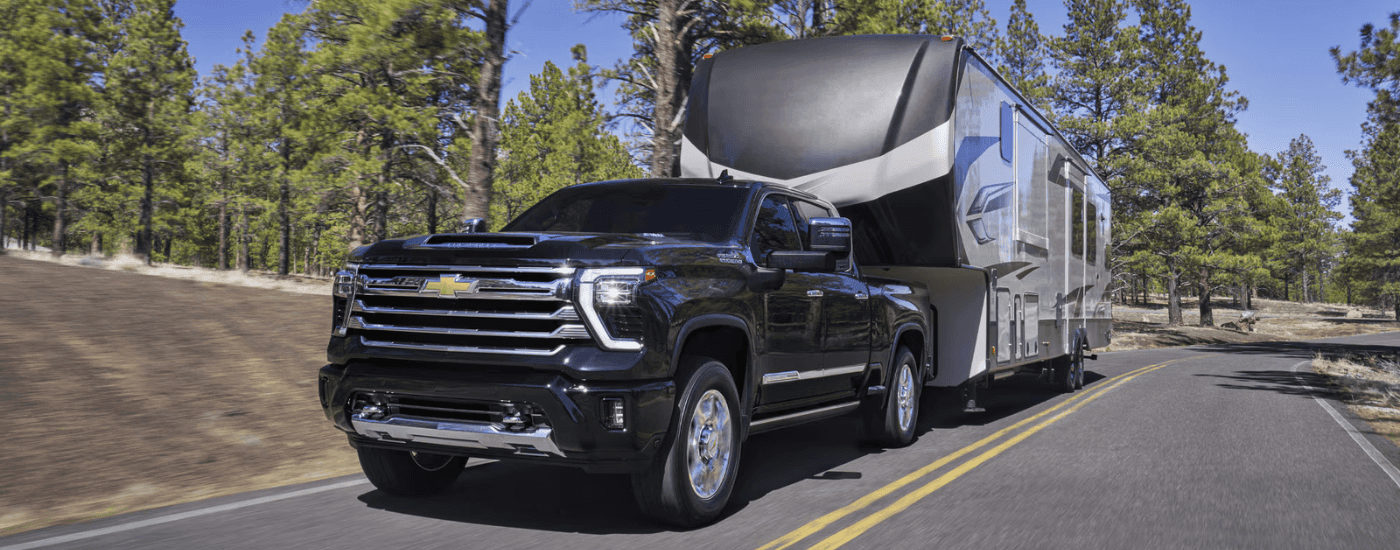 Black 2026 Chevy Silverado 3500 HD towing a large RV uphill