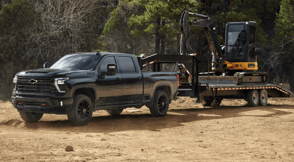 Black 2026 Chevy Silverado 2500 HD towing an excavator