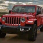 A red 2023 Jeep Wrangler driving on a bridge.