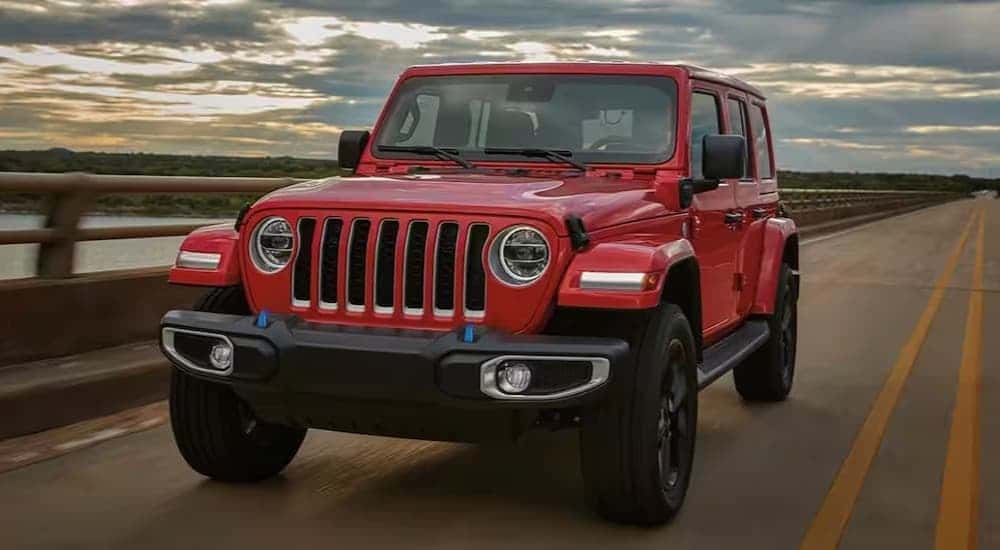 A red 2023 Jeep Wrangler driving on a bridge.