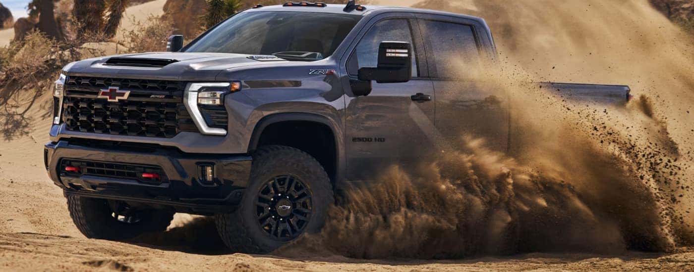 A gray 2026 Chevy Silverado 2500 HD ZR2 driving off-road in sand