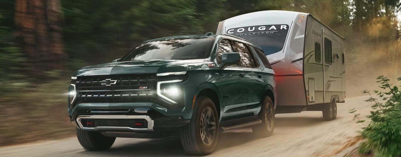 A green 2026 Chevy Tahoe Z71 towing a trailer.