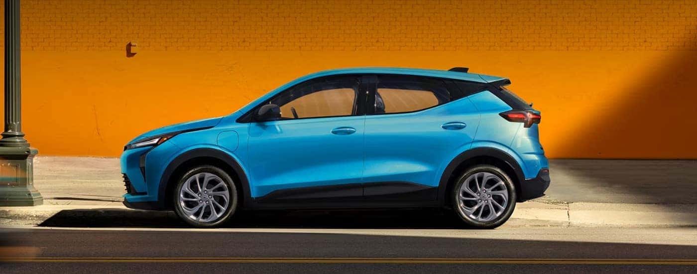 Blue 2027 Chevy Bolt for sale in Albany parked against a yellow wall