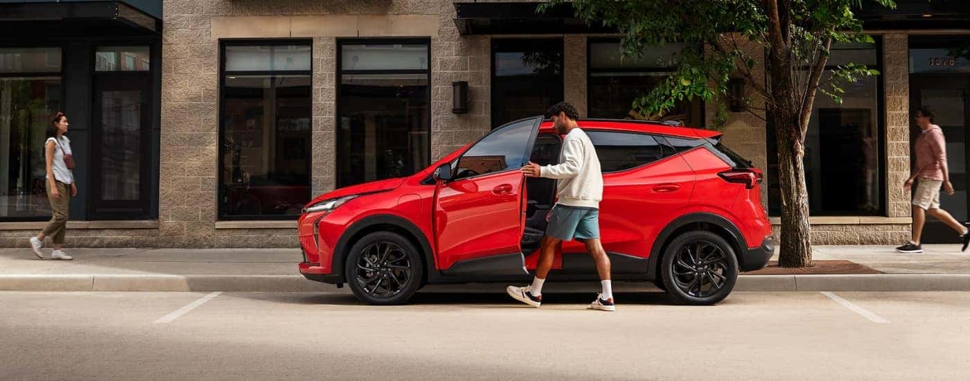 A person getting in to a red 2027 Chevy Bolt RS