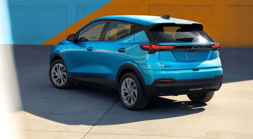 Rear of a blue 2027 Chevy Bolt for sale in Albany parked by a wall.