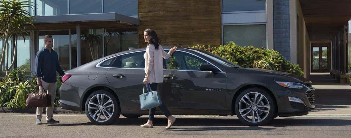 Two people standing near a gray 2024 Chevy Malibu.