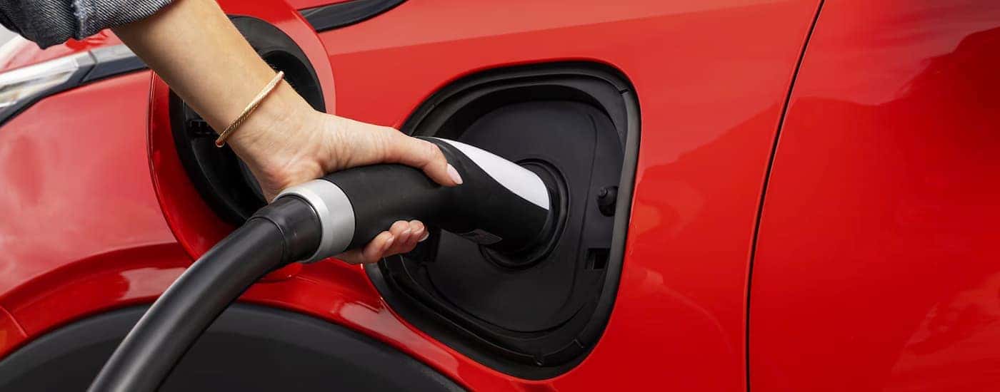 A red 2027 Chevy Bolt plugged in to charge