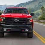 Front of a red 2020 Chevy Silverado 1500 Trail Boss driving down a road.