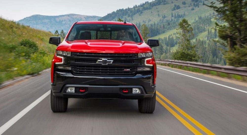 Front of a red 2020 Chevy Silverado 1500 Trail Boss driving down a road.