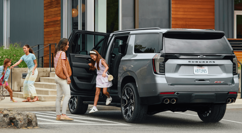 A family getting out of a silver 2026 Chevy Suburban