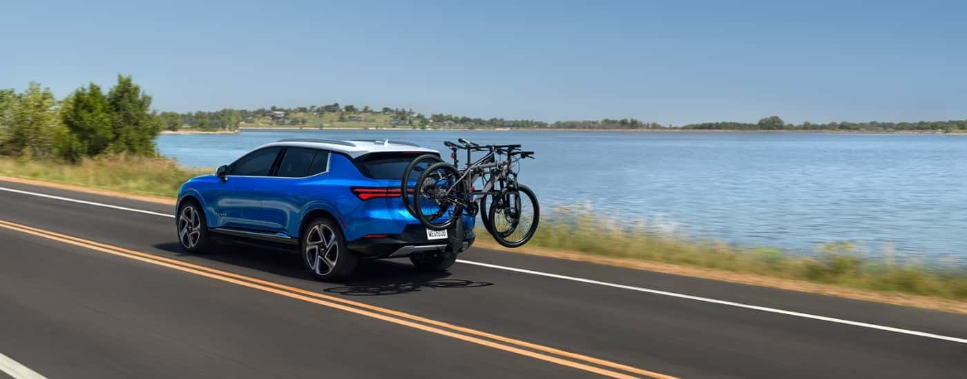 Blue 2024 Chevy Equinox EV driving past a lake