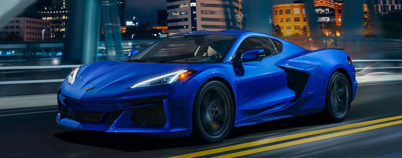 A blue 2026 Chevy Corvette E-Ray driving on a highway.