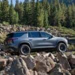 Grey 2026 Chevy Traverse driving up a rocky hill