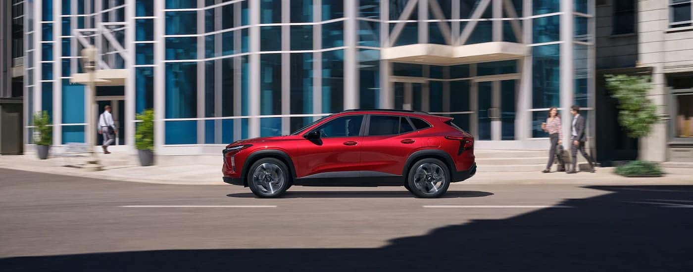 Side of a red 2025 Chevy Trax RS driving down a road.