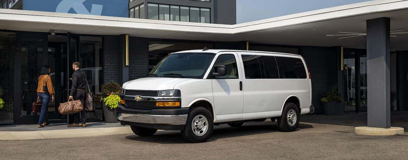 A white 2025 Chevy Conversion Van parked outside a building