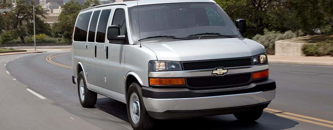 A gray 2025 Chevy Conversion Van driving down a street