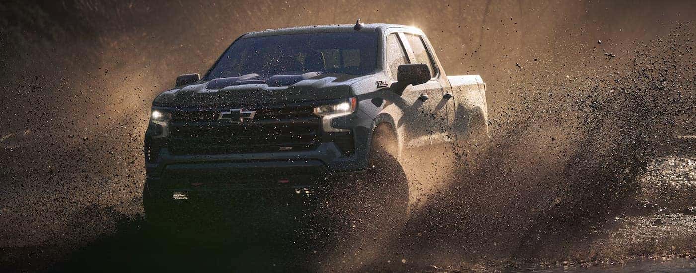A black 2026 Chevy Silverado 1500 Z71 off-roading in mud