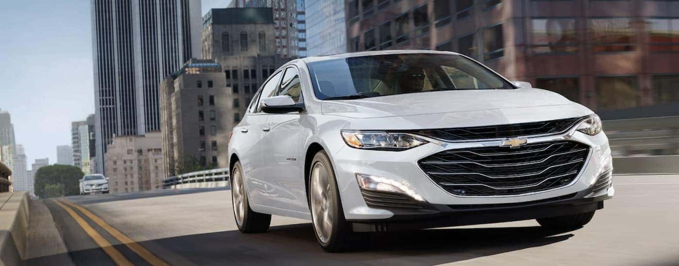 A white 2022 Chevy Malibu shown driving in a city.