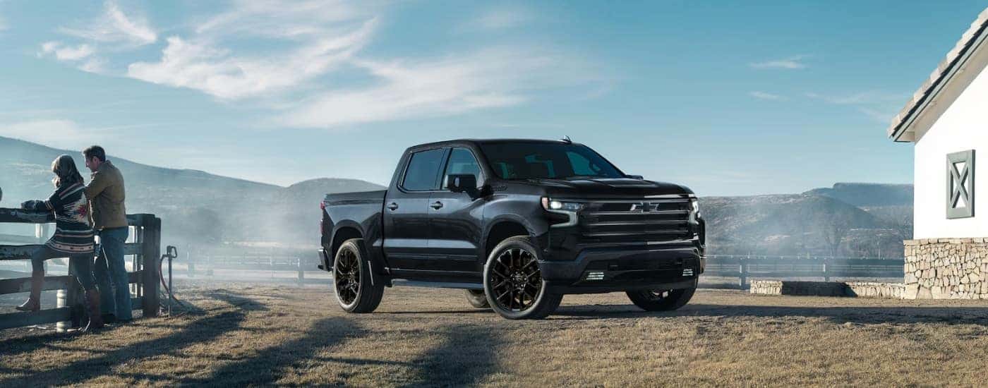 A black 2021 Chevy Silverado 1500 High Country parked by a fence.