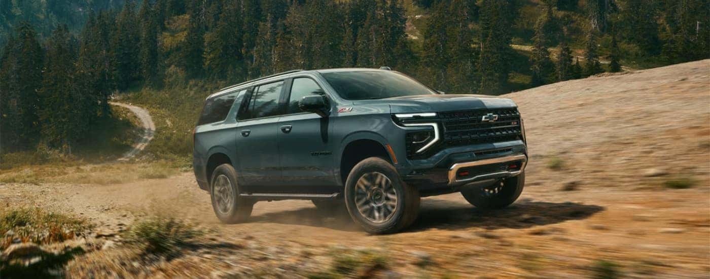 A green 2025 Chevy Suburban Z71 driving on a trail.