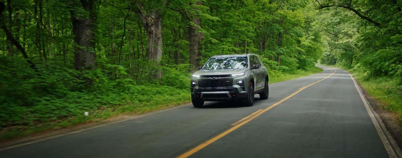 Green 2025 Chevy Traverse z71 driving on a tree-lined road.