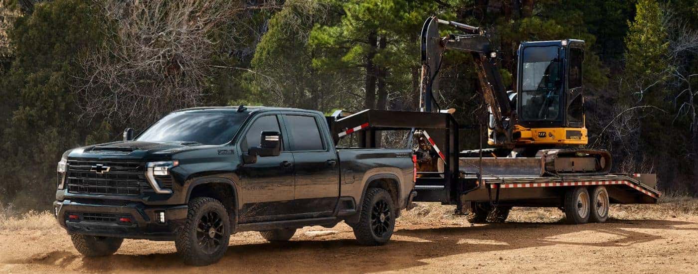 Green 2026 Chevy Silverado 2500 HD towing construction equipment.