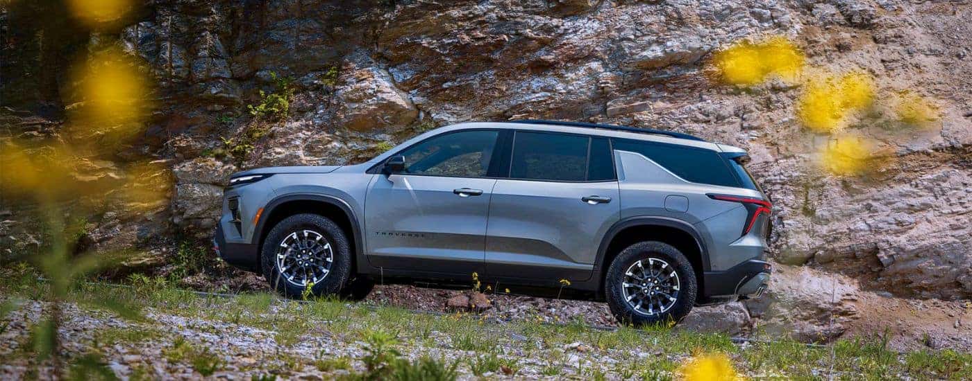 Grey 2026 Chevy Traverse driving up a rocky hill