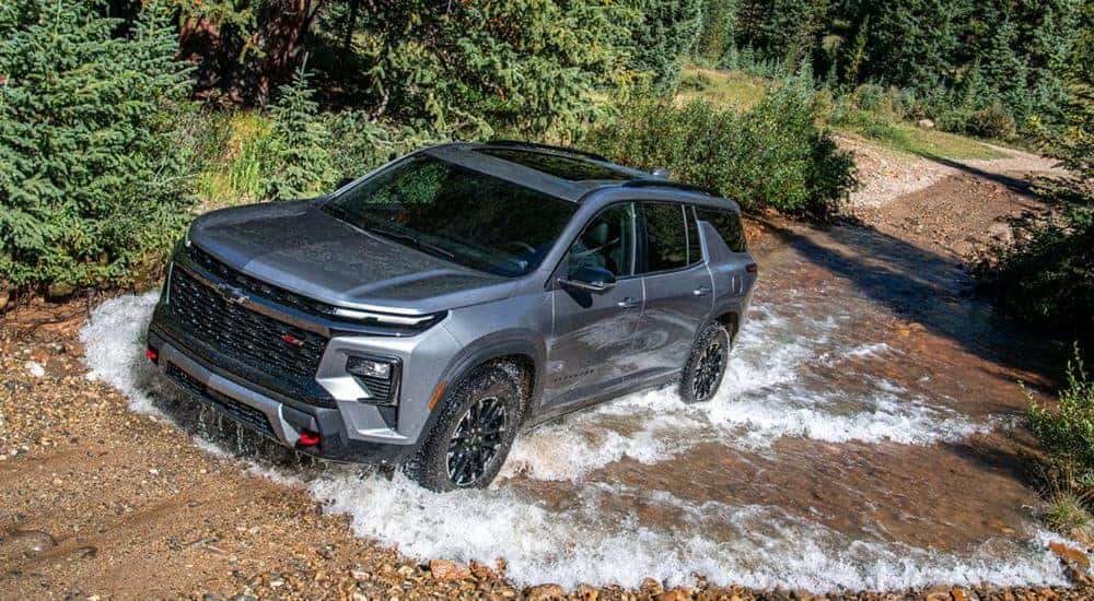 A gray 2026 Chevy Traverse Z71 driving through a dirt road puddle.