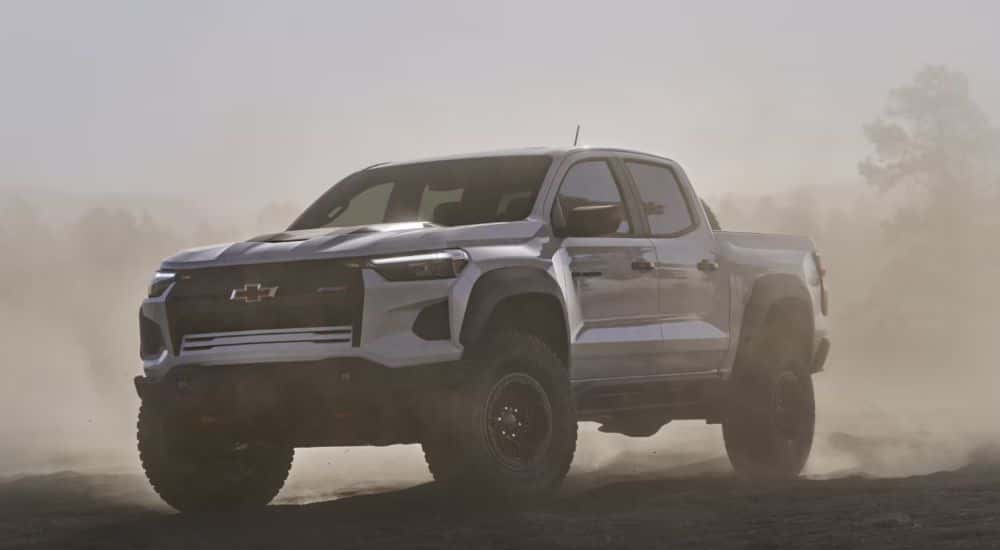 A white 2026 Chevy Colorado driving through a dust cloud.