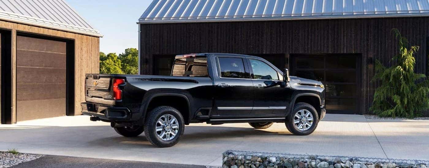 A black 2026 Chevy Silverado 2500 parked near a garage.