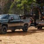 Green 2026 Chevy Silverado 2500 HD towing an excavator.