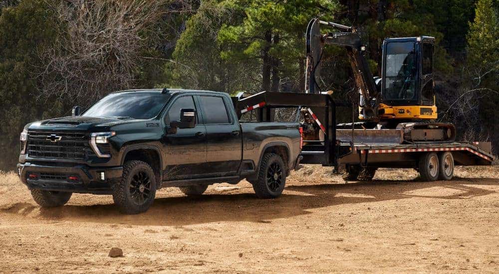 Green 2026 Chevy Silverado 2500 HD towing an excavator.